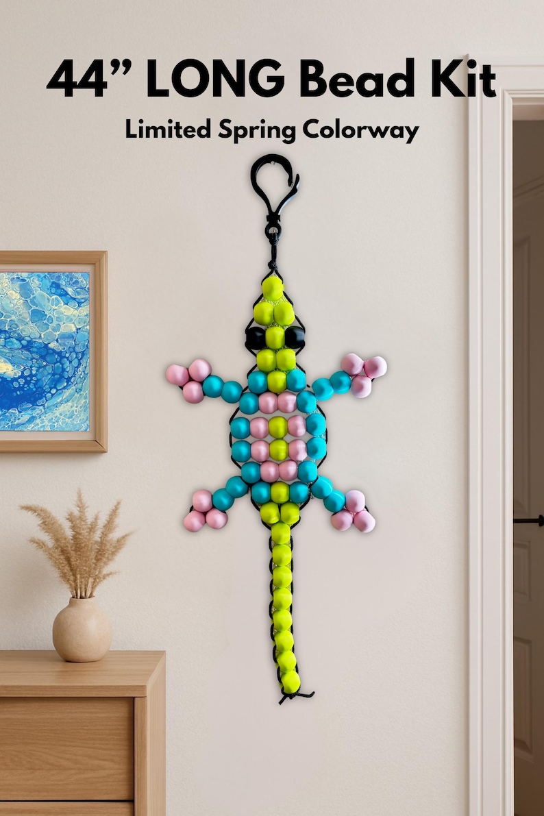 Puede incluir: Una decoraci&oacute;n de lagarto con cuentas, de aproximadamente 112 cm de largo, en una combinaci&oacute;n de colores de primavera limitada. El lagarto presenta un lazo negro para colgar y est&aacute; hecho con cuentas amarillas, rosas, azules y negras. El texto "44" LONG Bead Kit" y "Limited Spring Colorway" son visibles.