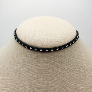 May include: A black choker necklace with silver studs.