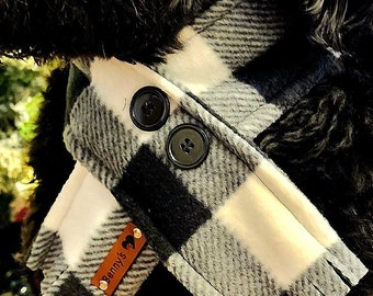 May include: Black and white plaid dog collar with a brown leather tag that says "Benny's" with a heart. The collar has two black buttons.