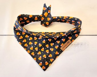 Puede incluir: Bandana negra con un patrón de maíz dulce y chispas. La bandana tiene una etiqueta de cuero marrón con el texto "Benny's" en ella.