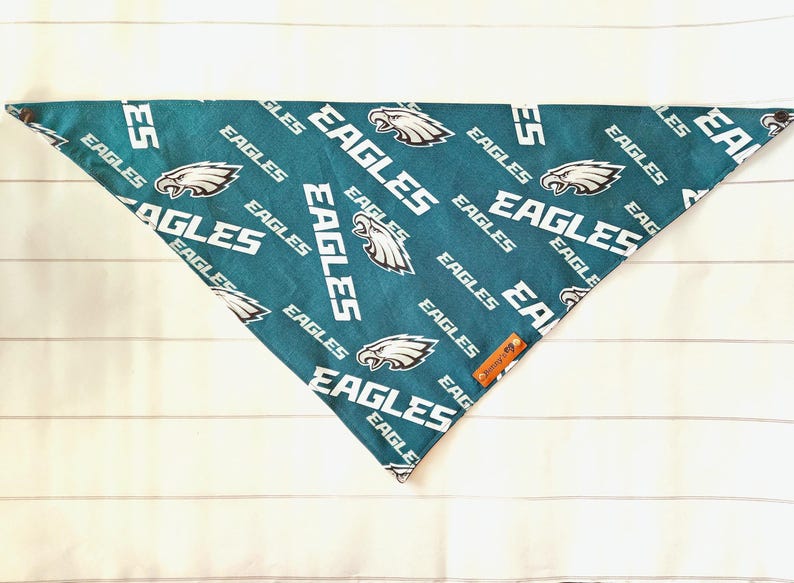 May include: Green and white dog bandana with a repeated pattern of the Philadelphia Eagles logo and the word "Eagles".