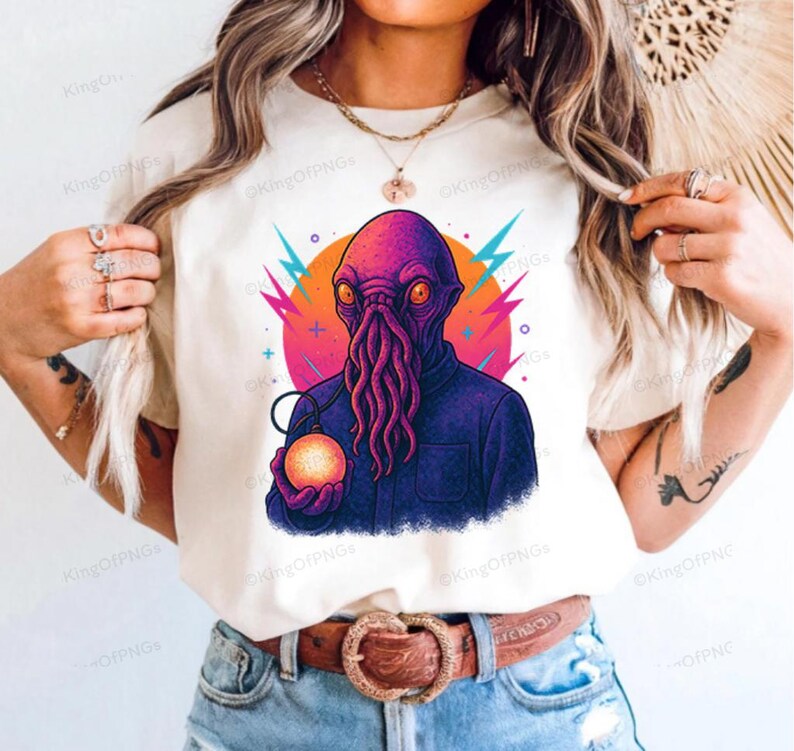A person wearing a white t-shirt with a colorful graphic of an alien-like creature holding a glowing orb.