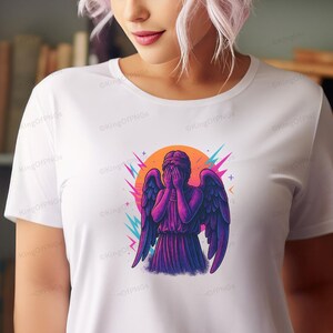 A woman wearing a white t-shirt with a graphic design of an angel with purple and blue wings.
