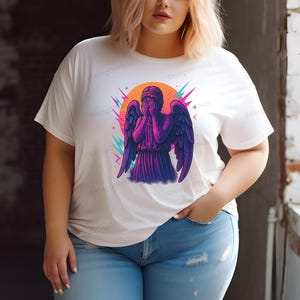 A woman wearing a white t-shirt with a graphic of an angel in purple and pink colors.