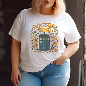 A woman wearing a white t-shirt with a graphic design featuring a blue telephone booth and the text "DOCTOR WHO" printed on it.