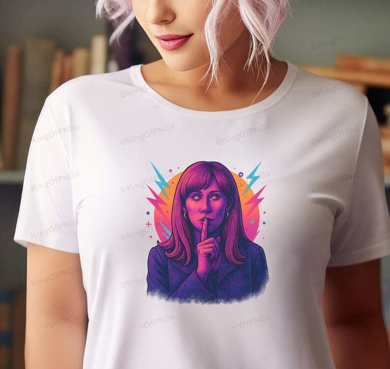 A woman with long hair wearing a white t-shirt with a colorful graphic of a woman making a hand gesture.