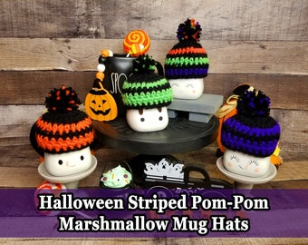 Könnte beinhalten: Eine Sammlung von Halloween-Marshmallow-Tassenhüten mit Streifenmustern und Bommeln. Die Hüte sind in verschiedenen Farben gehalten, darunter Orange, Grün und Lila, und werden auf weißen Tassen mit lächelnden Gesichtern präsentiert. Das Bild zeigt auch eine schwarze Tasse mit dem Wort "SPOOK" und einer dekorativen Kürbisdekoration.