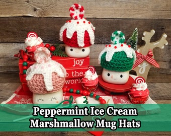 Puede incluir: Una exhibición festiva de sombreros de taza y cupcakes de ganchillo hechos a mano. Los sombreros, en rojo, rosa y verde, se asemejan a helado de menta. Las tazas tienen caras sonrientes. El texto "Peppermint Ice Cream Marshmallow Mug Hats" está en la parte inferior.