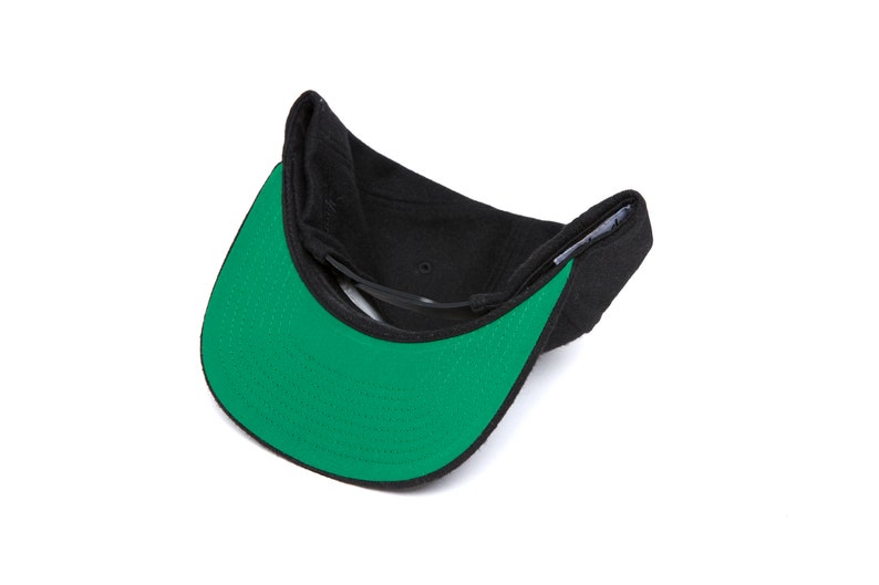 Peut inclure: Une casquette de baseball noire et verte avec une visi&egrave;re plate. La casquette est retourn&eacute;e &agrave; l'envers, montrant le dessous vert de la visi&egrave;re.