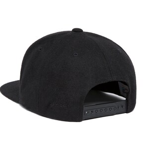 Peut inclure: Casquette de baseball noire avec une visi&egrave;re plate et une sangle r&eacute;glable noire &agrave; l'arri&egrave;re.