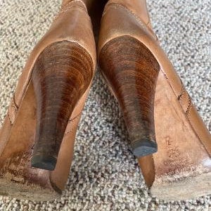 Puede incluir: Un par de botas de tac&oacute;n de cuero marr&oacute;n con punta puntiaguda. Las botas tienen un tac&oacute;n de madera y un eje de cuero marr&oacute;n.