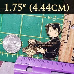 May include: Gold-toned enamel pin featuring a cartoon character in a black cassock holding a golden censer. The pin measures 1.75 inches (4.44 cm) and includes the text "AngelicCoffin.com by Shiroasa".