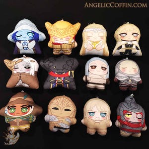 Może przedstawiać: Kolekcja pluszowych lalek z postaciami w stylu anime. Każda lalka ma unikalne stroje i wyrazy twarzy, z różnorodnością kolorów, w tym niebieskim, żółtym, brązowym i beżowym. Lalki są ułożone na czarnej powierzchni, z widocznym adresem strony internetowej ANGELICCOFFIN.COM.