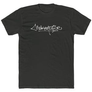 May include: A black short-sleeve t-shirt featuring the white text "Make Noise" written in a stylized, cursive graffiti-inspired font across the center of the chest. The shirt has a crew neckline and a standard fit with short sleeves.