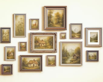 May include: A collection of framed landscape paintings in various sizes, arranged on a cream-colored wall. The artwork depicts scenes of forests, cabins, and deer, with warm, earthy tones and ornate frames. The arrangement creates a gallery wall effect.