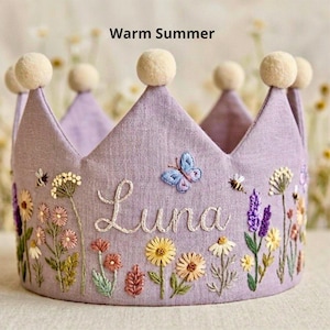 Peut inclure: Une couronne en tissu lavande avec des détails floraux et d'insectes brodés. La couronne porte le nom "Luna" en cursive et est ornée d'un papillon et d'abeilles. Le texte "Warm Summer" est en haut.