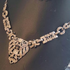 Collana con pendente geometrico in metallo stile Art Déco con pietre nere e trasparenti. 45 cm.