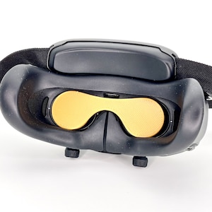 Könnte beinhalten: Schwarzes Virtual-Reality-Headset mit schwarzem Band und goldfarbenen Augenabdeckungen.