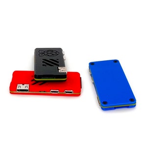 Op de afbeelding: Drie Raspberry Pi-behuizingen in verschillende kleuren: rood, zwart en blauw. De behuizingen zijn gemaakt van plastic en hebben verschillende poorten en connectoren.