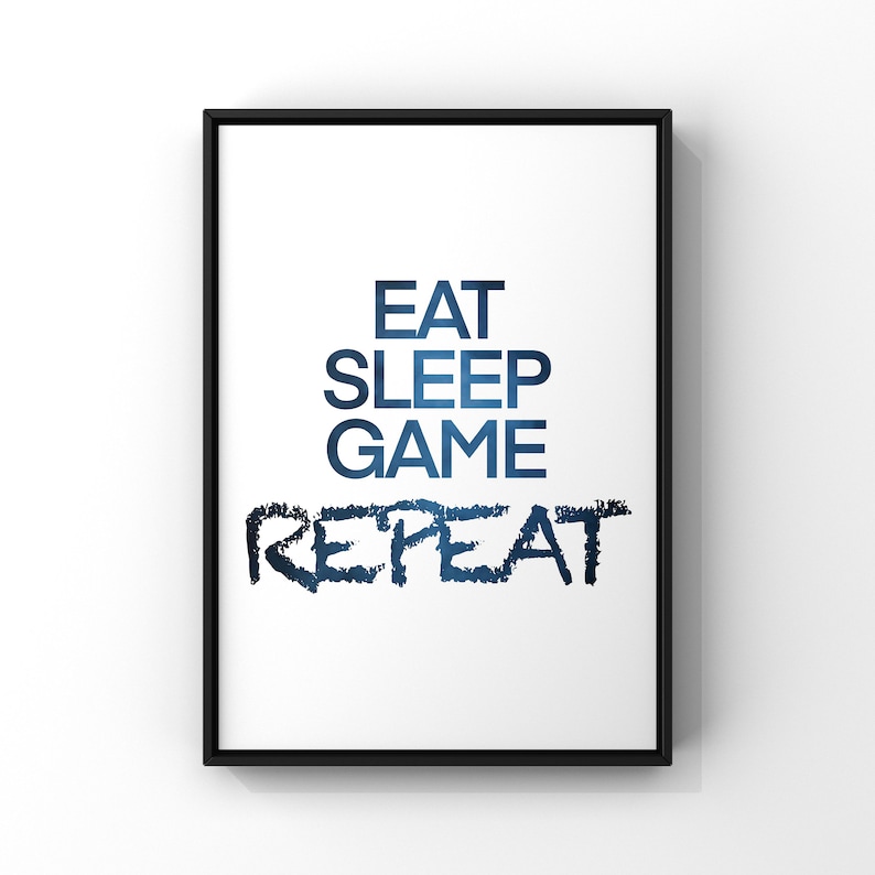May include: A black framed print with the text "Eat Sleep Game Repeat" in blue text with a gradient effect.