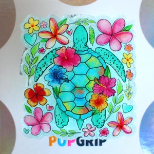 May include: A colorful sticker featuring a sea turtle design. The turtle is teal with a patterned shell, surrounded by vibrant flowers in pink, yellow, and orange, and green leaves. The sticker has the text "PopGrip" at the bottom.