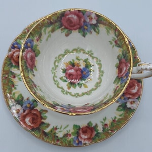 Può includere: Un set vintage di tazza da tè e piattino con un motivo floreale in tonalità di rosa, blu e verde. Il set ha un bordo dorato e un delicato motivo floreale.