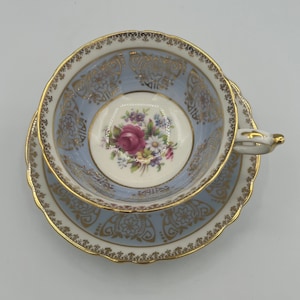 Può includere: Un set da tè in blu e bianco con bordi dorati e un motivo floreale. Il piattino ha un bordo smerlato.