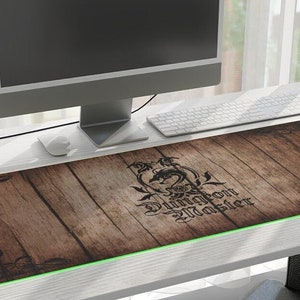 May include: A brown wooden desk mat with a green edge and a black and white dragon design. The text "Dragon Slayer" is printed on the mat.