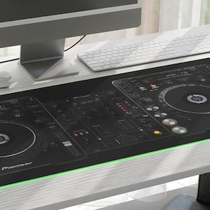 Puede incluir: Alfombrilla de escritorio negra y verde con un gráfico de dos consolas de mezclas Pioneer DJ. La alfombrilla tiene un brillo verde alrededor de los bordes.
