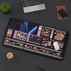May include: A black and purple mouse pad with a Star Trek themed design. The pad features a space scene with planets and stars, along with a variety of buttons and controls. The text "70" is visible in the lower right corner.