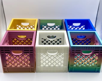 Op de afbeelding: Zes miniatuur melkkist organizers in verschillende kleuren, waaronder goud, roze, wit, groen, blauw en grijs. De kisten zijn gemaakt van plastic en hebben een rasterpatroon.