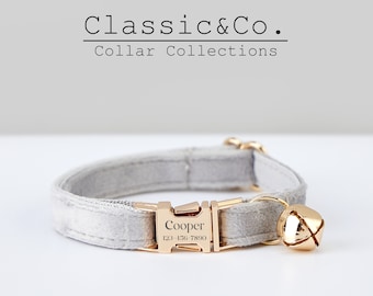 Könnte beinhalten: Ein graues Samtkatzenhalsband mit einer goldenen Schnalle und einer Glocke. Die Schnalle trägt den Namen "Cooper" und eine eingravierte Telefonnummer.