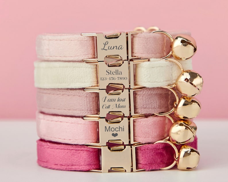 May include: Five pink, white, and red velvet cat collars with gold buckles and bells. The collars are engraved with the names Luna, Stella, "I am lost Call Mom", and Mochi.