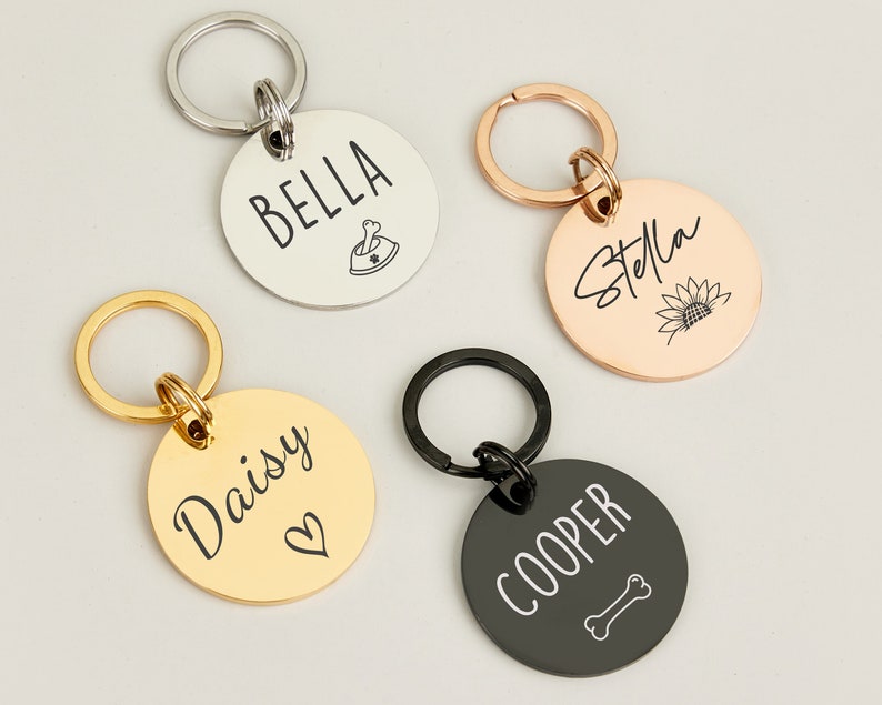 May include: Four personalized dog tag keychains with different names and designs. The keychains are silver, gold, rose gold, and black.