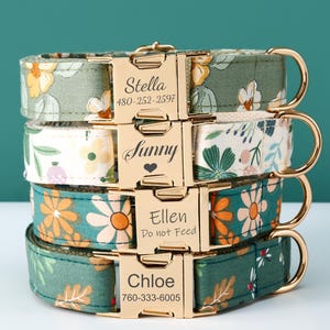 May include: Four stacked dog collars with floral patterns in green, white, and orange. Each collar features a gold-coloured buckle engraved with a name and phone number or a message. The collars are stacked on top of each other.