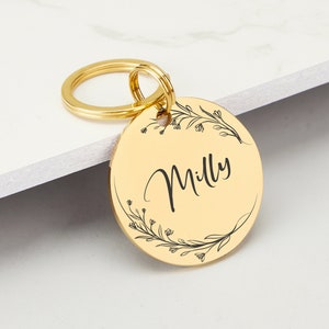 May include: Gold-colored metal pet tag with a floral design and the name "Milly" engraved on it.
