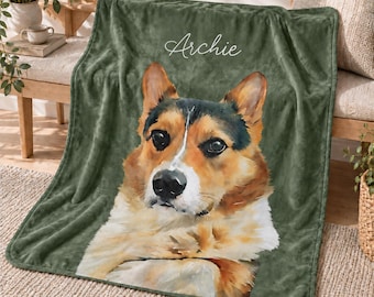 May include: A soft olive green fleece blanket featuring a large, detailed watercolor-style portrait of a tricolor dog with black, brown, and white fur. The name Archie is printed in white cursive script above the dog's head on the fabric.