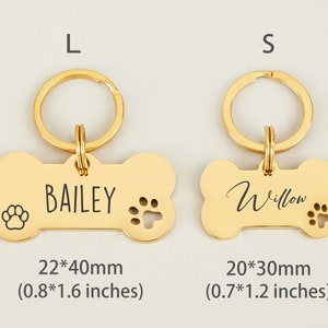 May include: Two gold bone-shaped dog tags with key rings. The larger tag is 0.8 by 1.6 inches and says "BAILEY". The smaller tag is 0.7 by 1.2 inches and says "Willow".