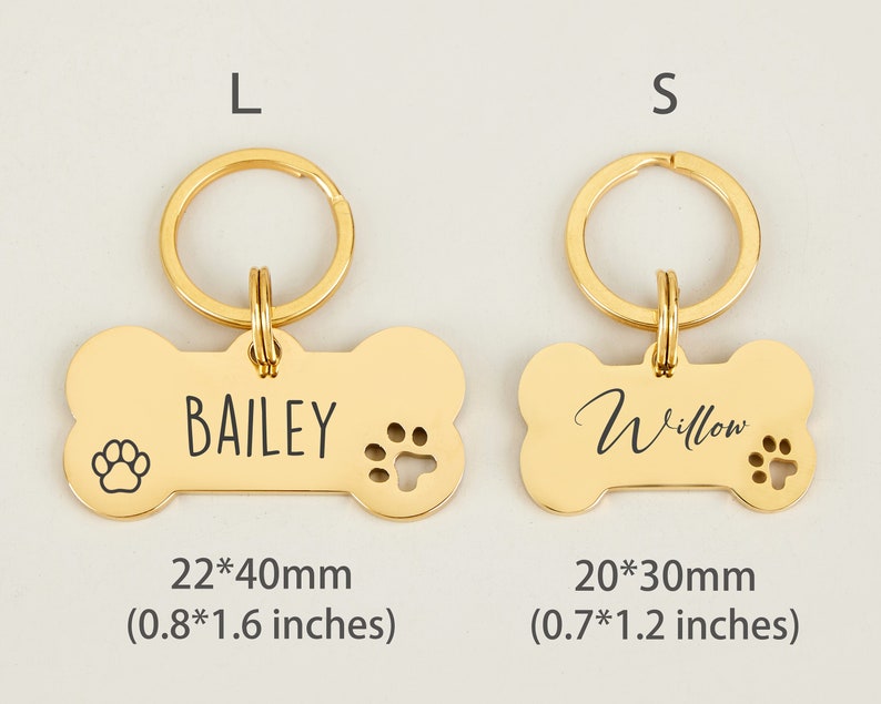 May include: Two gold bone-shaped dog tags with key rings. The larger tag is 0.8 by 1.6 inches and says "BAILEY". The smaller tag is 0.7 by 1.2 inches and says "Willow".
