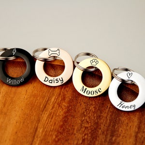Puede incluir: Cuatro llaveros de identificación para perros personalizados con diferentes diseños y nombres: Willow, Daisy, Moose y Honey. Los llaveros son de metal y tienen forma redonda.