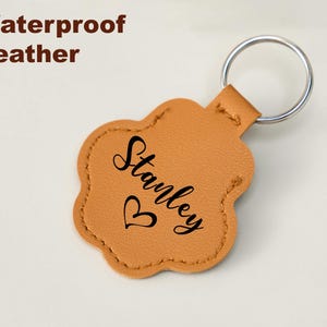 May include: Tan leather paw-shaped keychain with a silver key ring. The keychain is personalized with the name "Stanley" in black script and a small heart. The words "Waterproof Leather" are in brown text.
