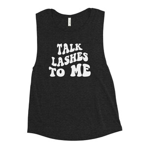 May include: A dark gray sleeveless muscle tank top with the text "TALK LASHES TO ME" in white, stylized lettering.