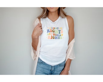 May include: White tank top with a colorful graphic that reads "Reproductive Rights Are Human Rights".