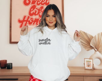 May include: White hooded sweatshirt with the text "sweater weather" in black cursive lettering.
