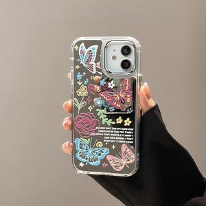 Puede incluir: Una funda transparente para teléfono con un diseño de mariposa colorida y texto que dice "SJE ZIHT TOO SVT HON CHA YESHS VN 10 TUO TEO THASI JOYFIHI TANT EHUTS STINT DOV 220 AKAMI TANT SUSH SUT STAHY VERE".