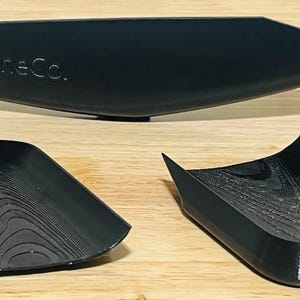 May include: Three black plastic trays, one long and two smaller, with a textured surface. The long tray has the text "EliteOneCo." printed on it.
