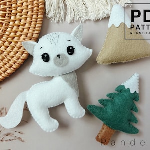 May include: A PDF pattern and instructions for making felt animal toys. The pattern includes a white cat, a green tree with a white top, and a brown mountain with a white top.