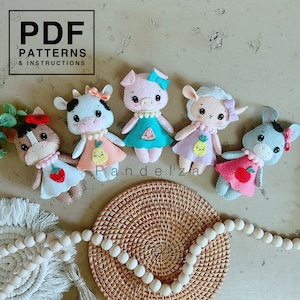 May include: Five felt animal toys with different fruit designs. The toys are a pig with a watermelon, a cow with a pineapple, a lamb with a pineapple, a donkey with an apple, and a horse with a strawberry. The toys are arranged on a woven surface with a wooden bead garland.