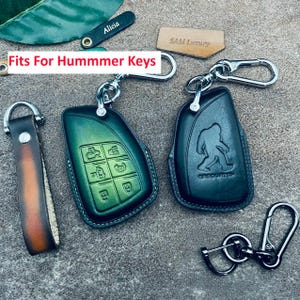Può includere: Portachiavi in pelle verde e nera per chiavi Hummer. Un portachiavi verde presenta simboli di chiavi, l'altro nero ha un design Bigfoot. Include portachiavi e un cinturino in pelle. Il testo dell'immagine recita "Fits For Hummer Keys".