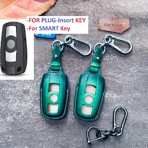 May include: Two green leather key covers with silver key rings and a black key fob. The key covers have a silver button and the text "SAM Luxury" is on a brown leather tag.